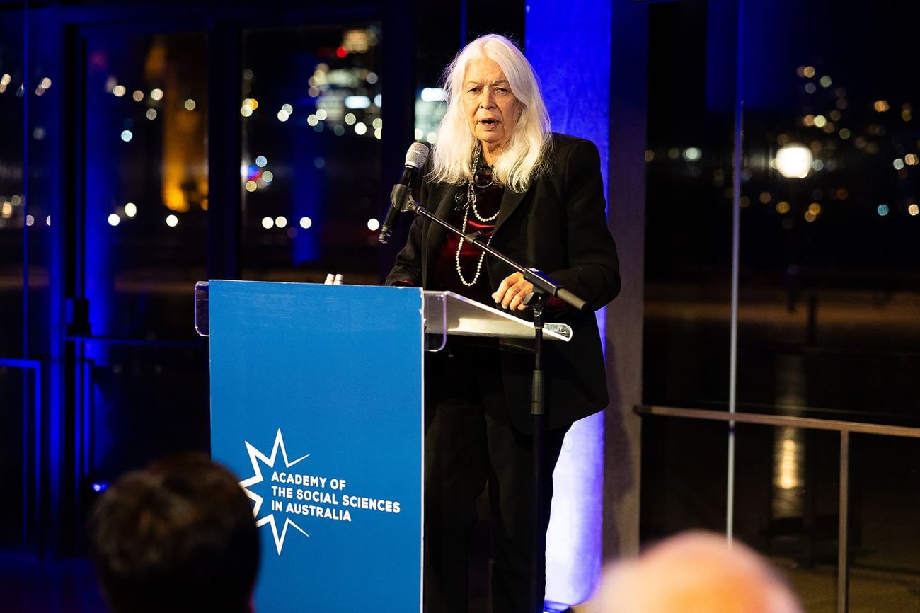 Professor Marcia Langton speaks in front of a lectern with the Academy of the Social Sciences in Australia banner.