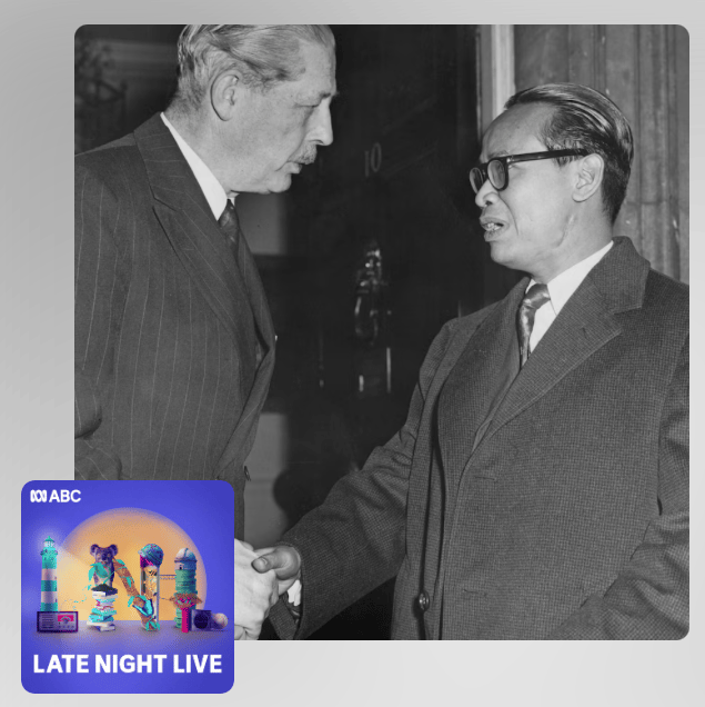 A promotional image for the Late Night Live Program. The program logo sits in front of a black and white photograph of two men, one of Caucasian and one of Asian appearance, shaking hands. Both men wear dark suits. The Asian man wears thick rimmed dark glasses.